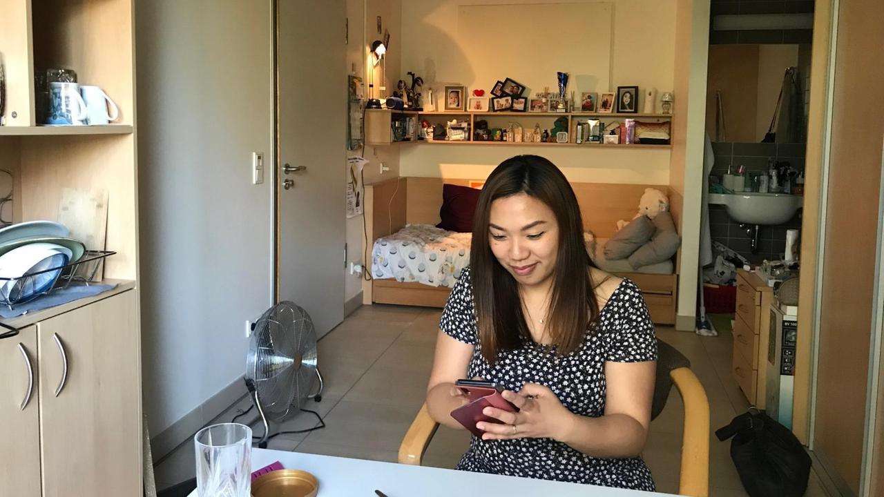 Daisy sitzt an einem Tisch im Schwesternwohnheim und chattet per Smartphone mit ihrer Familie. Daisy sitzt an einem Tisch im Schwesternwohnheim und chattet per Smartphone mit ihrer Familie.