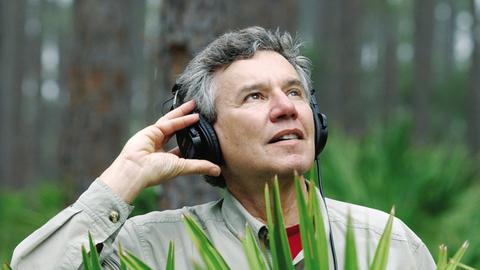 Der Musiker und Naturforscher Bernie Krause mit Kopfhörern in der Natur.