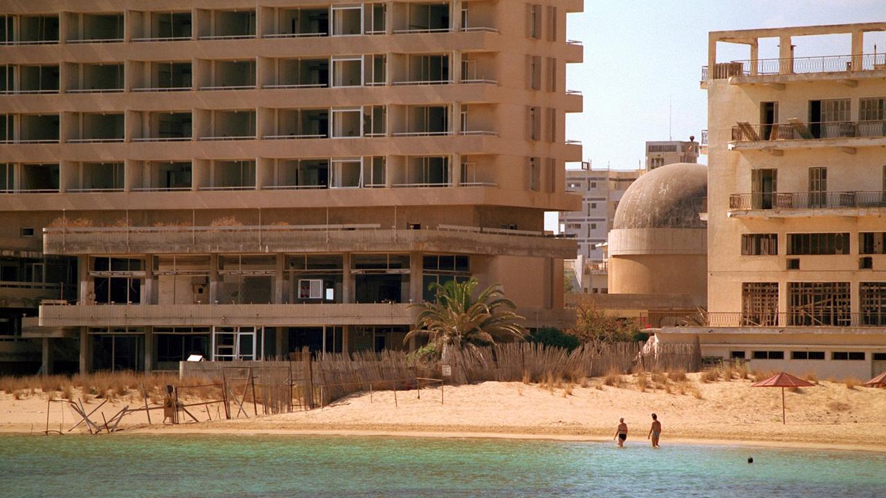 Zwei Touristen waten im Oktober 1998 in Strandnähe durch das flache Wasser. Sie nähern sich dabei der durch einen Stacheldrahtzaun markierten Demarkationslinie, die ihren Hotelkomplex (r) in Gazimagusa (ehemals Famagusta) von den leerstehenden Hotelruinen (l) der früheren Touristenstadt Varosha (Vorort von Famagusta) trennt. Zwei Touristen waten im Oktober 1998 in Strandnähe durch das flache Wasser. Sie nähern sich dabei der durch einen Stacheldrahtzaun markierten Demarkationslinie, die ihren Hotelkomplex (r) in Gazimagusa (ehemals Famagusta) von den leerstehenden Hotelruinen (l) der früheren Touristenstadt Varosha (Vorort von Famagusta) trennt.