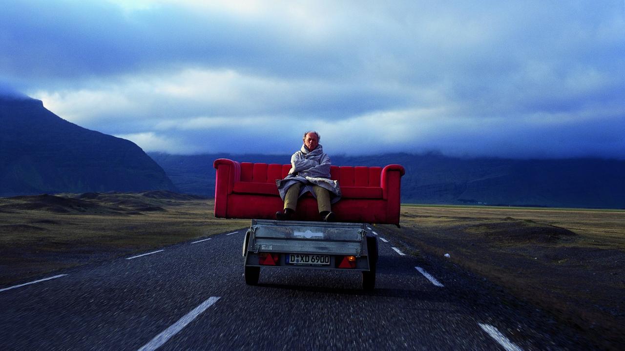 Horst Wackerbarth mit seinem roten Sofa auf einer einsamen Landstraße in Island 2003.