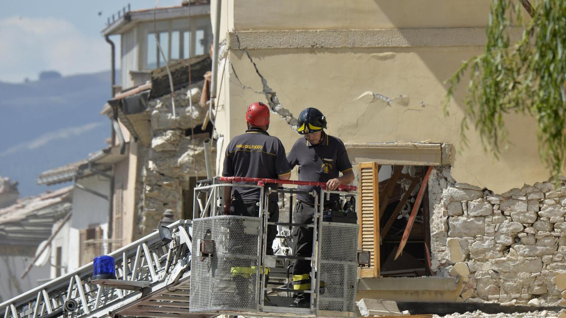 Feuerwehrleute untersuchen ein beschädigtes Gebäude in Amatrice. Feuerwehrleute untersuchen ein beschädigtes Gebäude in Amatrice.