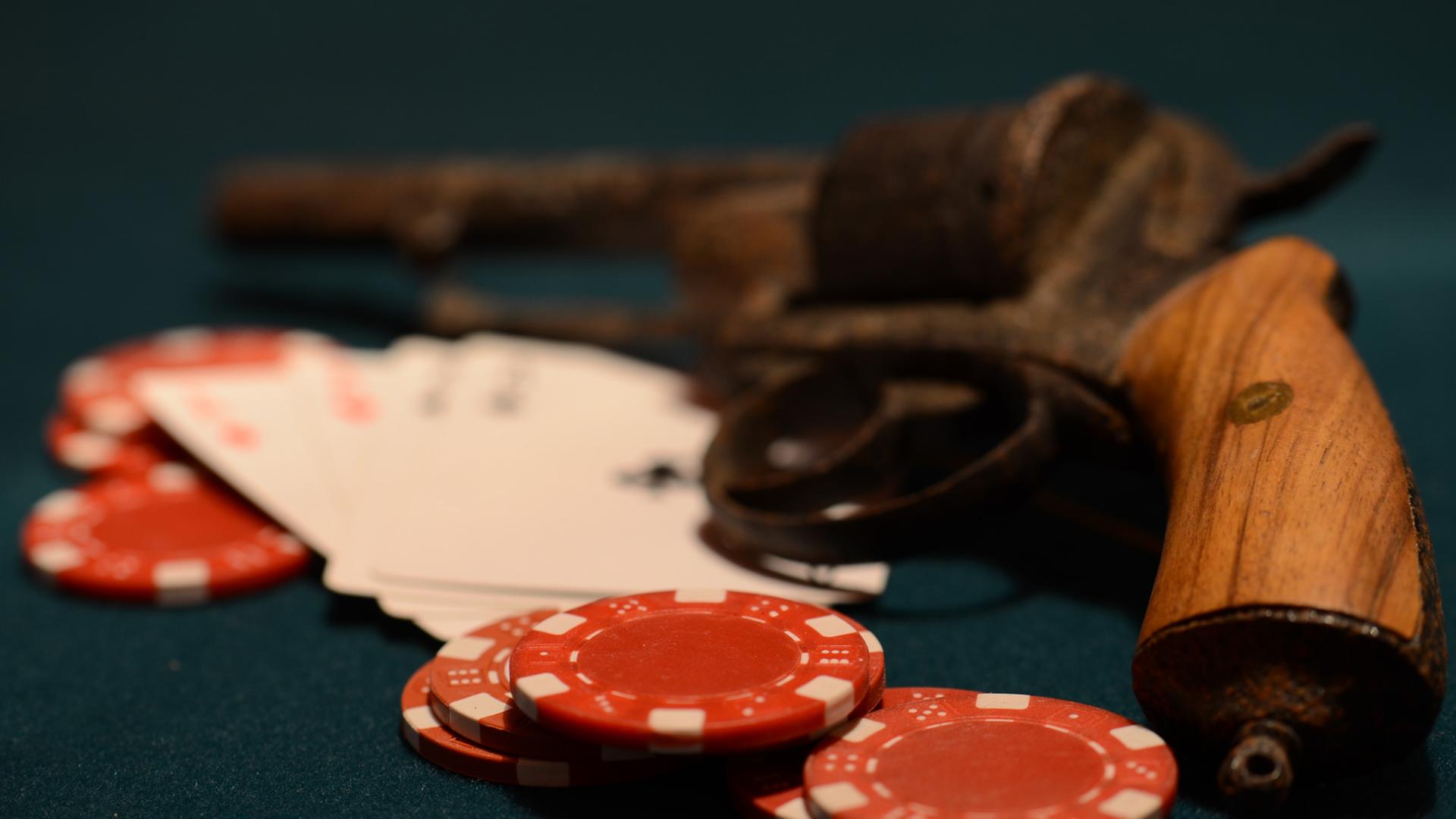 Im Kasino: Jetons und Spielkarten liegen vor einer Pistole. Im Kasino: Jetons und Spielkarten liegen vor einer Pistole.