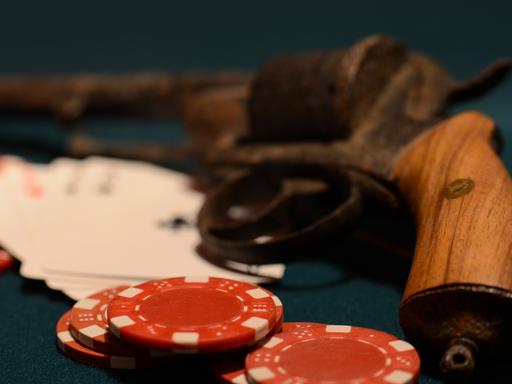 Im Kasino: Jetons und Spielkarten liegen vor einer Pistole.