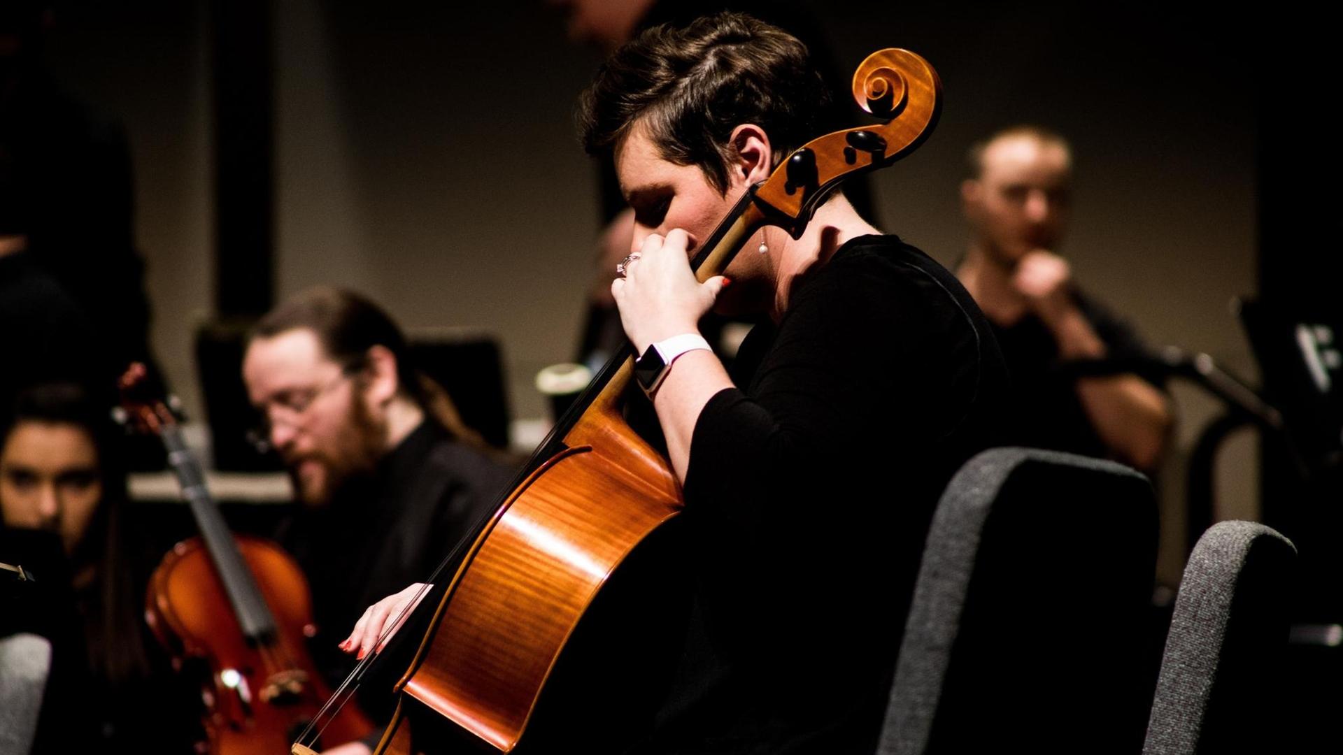 Im Bildvordergrund ist eine Cellistin zu sehen, im Hintergrund drei weitere Musiker mit Streichiinstrumenten. Im Bildvordergrund ist eine Cellistin zu sehen, im Hintergrund drei weitere Musiker mit Streichiinstrumenten.