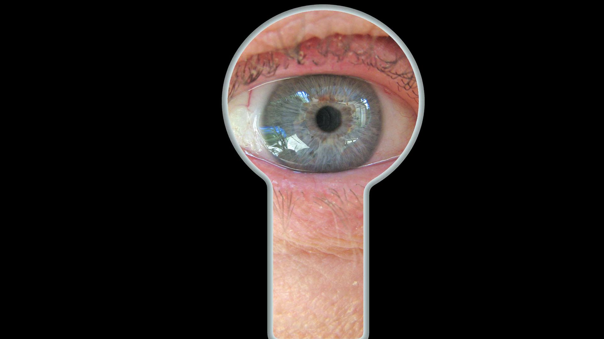 Ein Auge blickt durch eine Schlüsselloch. Ein Auge blickt durch eine Schlüsselloch.