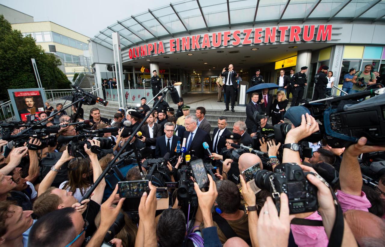 Bundesinnenminister Thomas de Maiziere (CDU, Mitte, l) und Bayerns Innenminister Joachim Herrmann (CSU, Mitte, r) geben einen Tag nach einer Schießerei mit Toten und Verletzten, vor dem Olympia-Einkaufszentrum (OEZ) in München (Bayern) ein Statement ab. Bundesinnenminister Thomas de Maiziere (CDU, Mitte, l) und Bayerns Innenminister Joachim Herrmann (CSU, Mitte, r) geben einen Tag nach einer Schießerei mit Toten und Verletzten, vor dem Olympia-Einkaufszentrum (OEZ) in München (Bayern) ein Statement ab.
