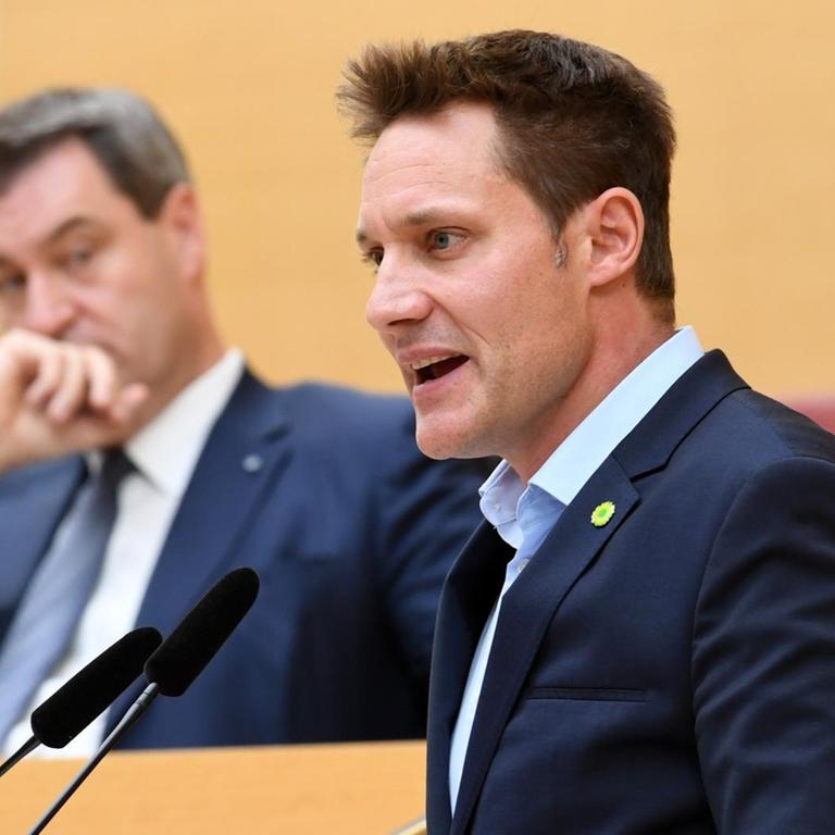 Markus Söder (CSU, l), bayerischer Ministerpräsident, verfolgt die Rede des Fraktionsvorsitzenden von Bündnis 90/Die Grünen im Landtag, Ludwig Hartmann