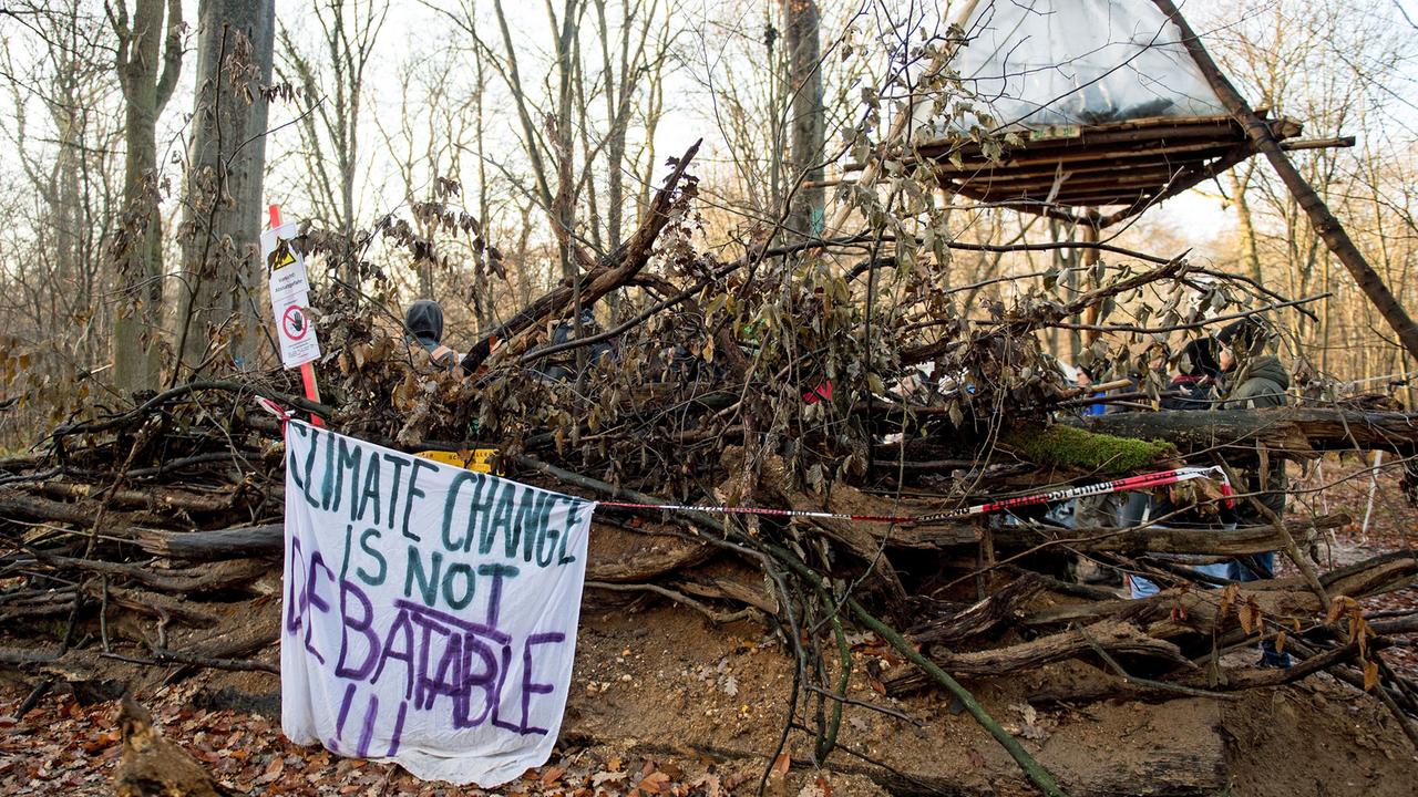 Ein Banner mit der Aufschrift "Climate Change is not debatable" hängt am 28.11.2017 im Hambacher Forst in Kerpen (Nordrhein-Westfalen) an einer Barrikade. Im Hambacher Wald haben am Montag die umstrittenen Rodungsarbeiten begonnen. Rund 200 Demonstranten aus der Waldbesetzer-Szene versuchen diese zu verhindern. Foto: Marius Becker/dpa Ein Banner mit der Aufschrift "Climate Change is not debatable" hängt am 28.11.2017 im Hambacher Forst in Kerpen (Nordrhein-Westfalen) an einer Barrikade. Im Hambacher Wald haben am Montag die umstrittenen Rodungsarbeiten begonnen. Rund 200 Demonstranten aus der Waldbesetzer-Szene versuchen diese zu verhindern. Foto: Marius Becker/dpa