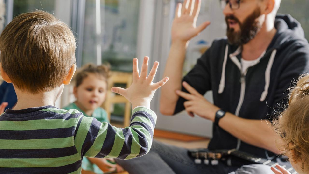 Kinder spielen mit einem Erzieher "Abklatschen" Kinder spielen mit einem Erzieher "Abklatschen"