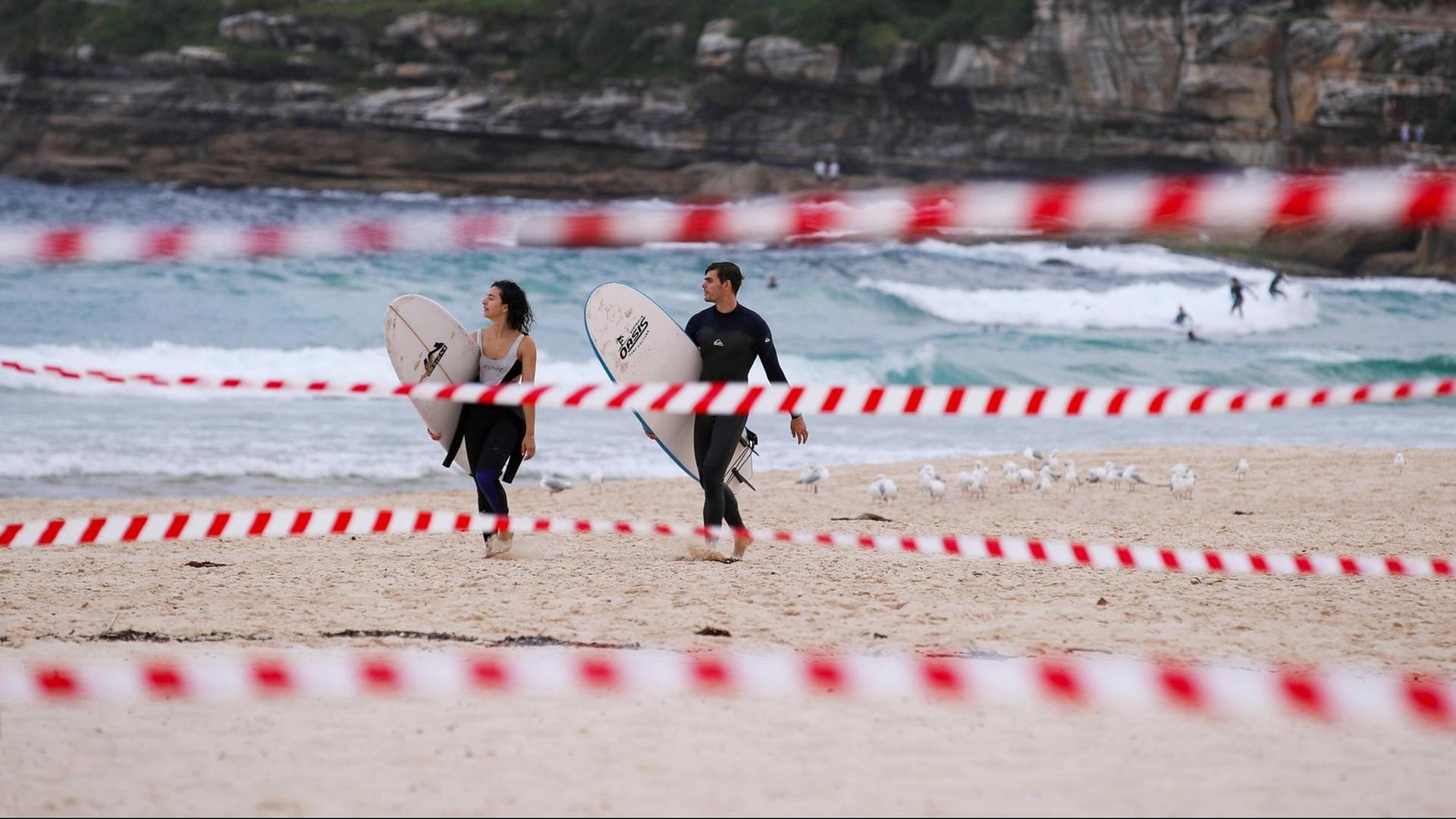 Eine wenige Surfer am Bondi Beach in Sydney, Australien, im Vordergrund ist Absperrband zu sehen, aufgenommen im April 2020 Eine wenige Surfer am Bondi Beach in Sydney, Australien, im Vordergrund ist Absperrband zu sehen, aufgenommen im April 2020