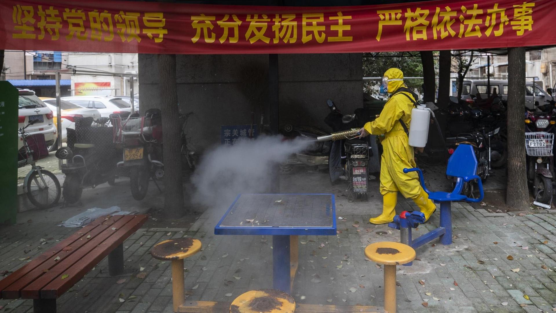 Das Bild zeigt einen Mann mit Schutzkleidung in der chinesischen Stadt Wuhan. Er desinfiziert mit eine Straße. STR / AFP) / China OUT Das Bild zeigt einen Mann mit Schutzkleidung in der chinesischen Stadt Wuhan. Er desinfiziert mit eine Straße. STR / AFP) / China OUT