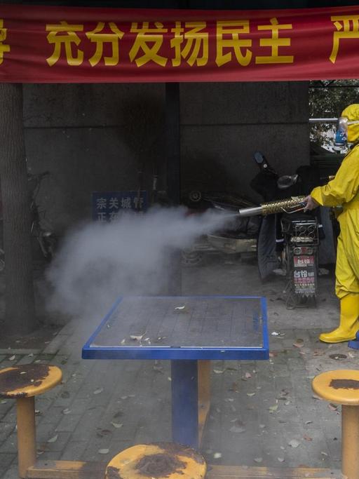 Das Bild zeigt einen Mann mit Schutzkleidung in der chinesischen Stadt Wuhan. Er desinfiziert mit eine Straße. STR / AFP) / China OUT
