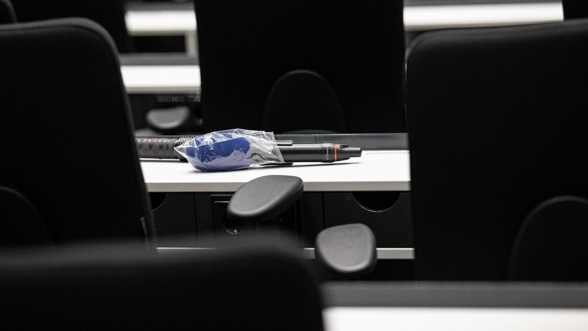 Das Mikrofon eines Fernsehsenders liegt, eingehüllt in eine Plastiktüte, während einer Pressekonferenz zur Entwicklung der Coronakrise in Niedersachsen, auf einem Tisch.