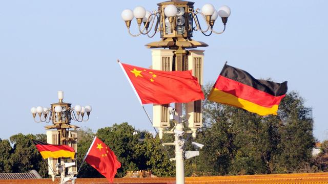 Deutsche und chinesische Flagge wehen an Lampen auf dem Tiananmen-Platz in Peking