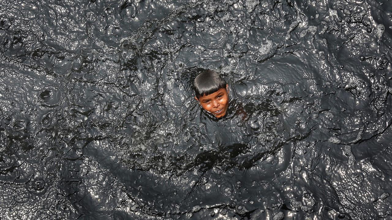 Ein Junge streckt seinen Kopf aus dem schwarzen Wasser des Flusses Yamuna in Neu Delhi.