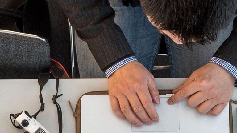 Ein Mann sitzt an einem Computer, daneben eine Kamera. Ein Mann sitzt an einem Computer, daneben eine Kamera.