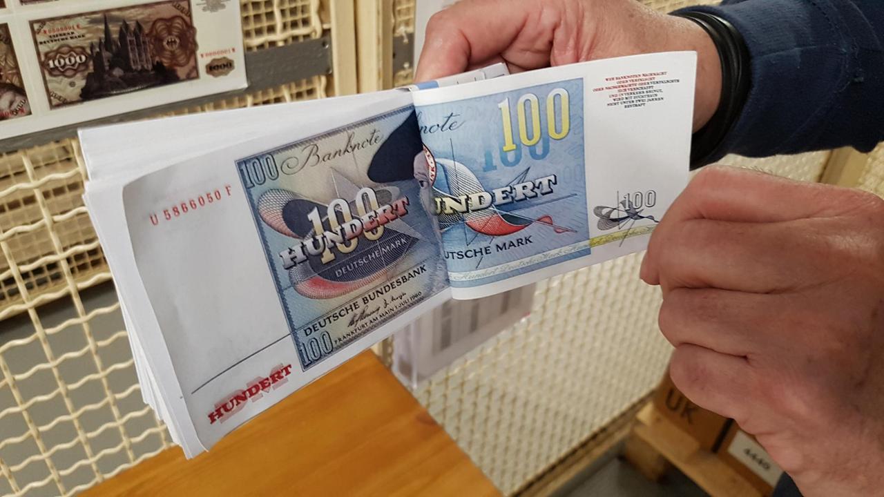 Mann hält einen Bündel von 100 Mark-Noten in der Hand und blättert durch. Mann hält einen Bündel von 100 Mark-Noten in der Hand und blättert durch.