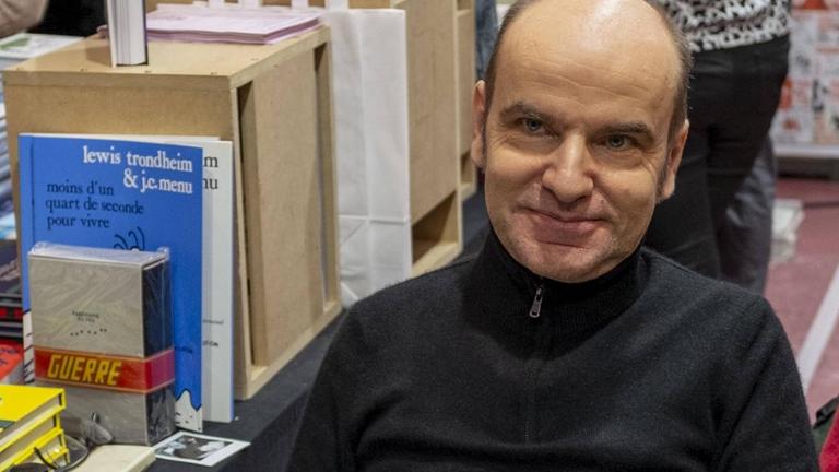 Ein Mann sitzt an einem Bücherstand. Ein Mann sitzt an einem Bücherstand.