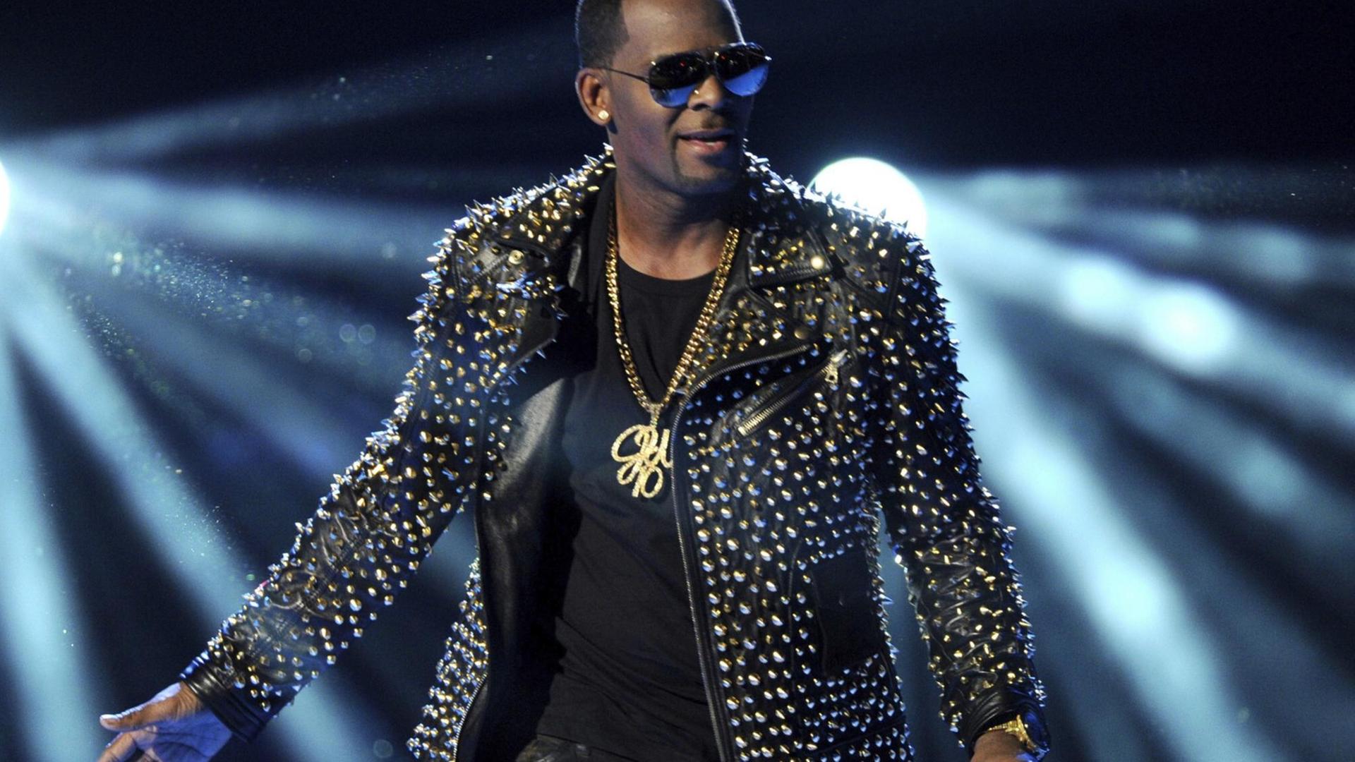 Der US-Musiker R. Kelly steht im Lichtschein auf einer Bühne. Der US-Musiker R. Kelly steht im Lichtschein auf einer Bühne.