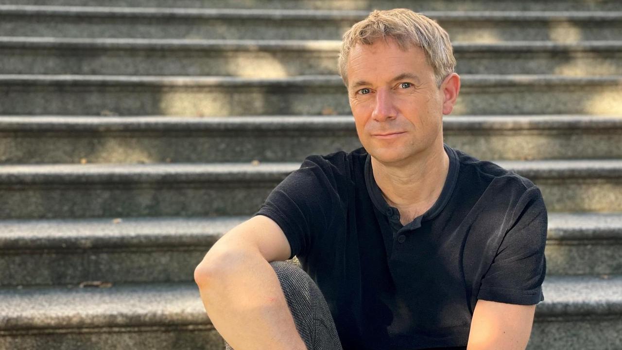 Der Verleger und Autor Jo Lendle posiert auf Treppenstufen sitzend. Der Verleger und Autor Jo Lendle posiert auf Treppenstufen sitzend.