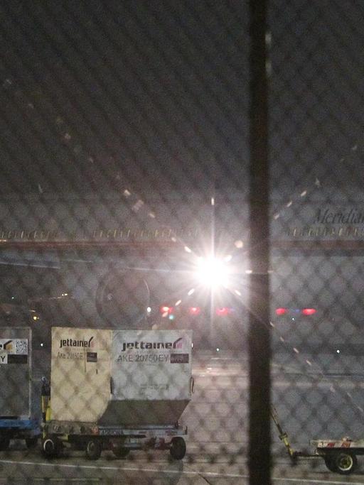 Das Flugzeug steht in der Dunkelheit hinter einem Zaun auf dem Frankfurter Flughafen. 