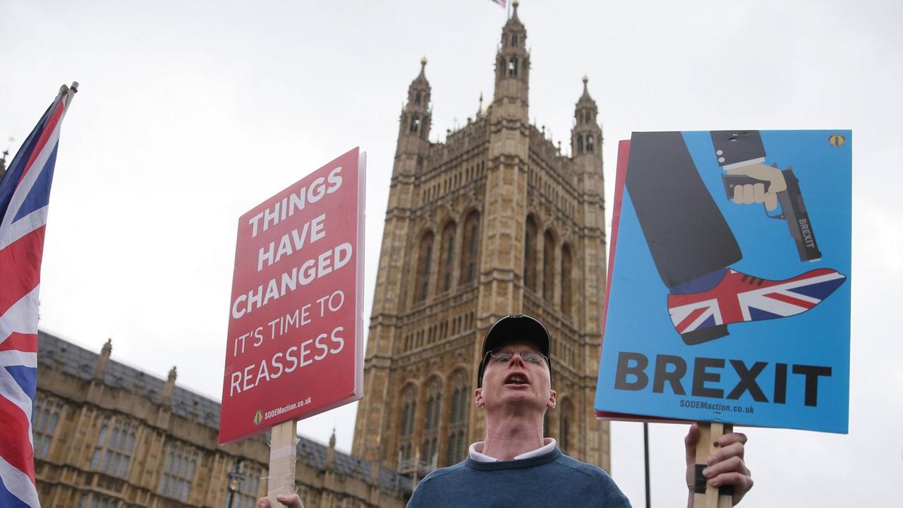 Ein Brexit-Gegner steht vor dem Houses of Parliaments in London und hält Schilder hoch