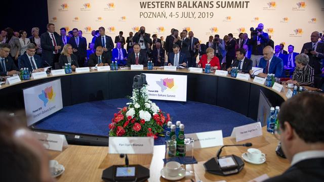 Bundeskanzlerin Angela Merkel sitzt in einem roten Jackett an einem großen runden Tisch zwischen weiteren Spitzenpolitikern der EU sowie der Staaten des Westbalkans-Staaten.