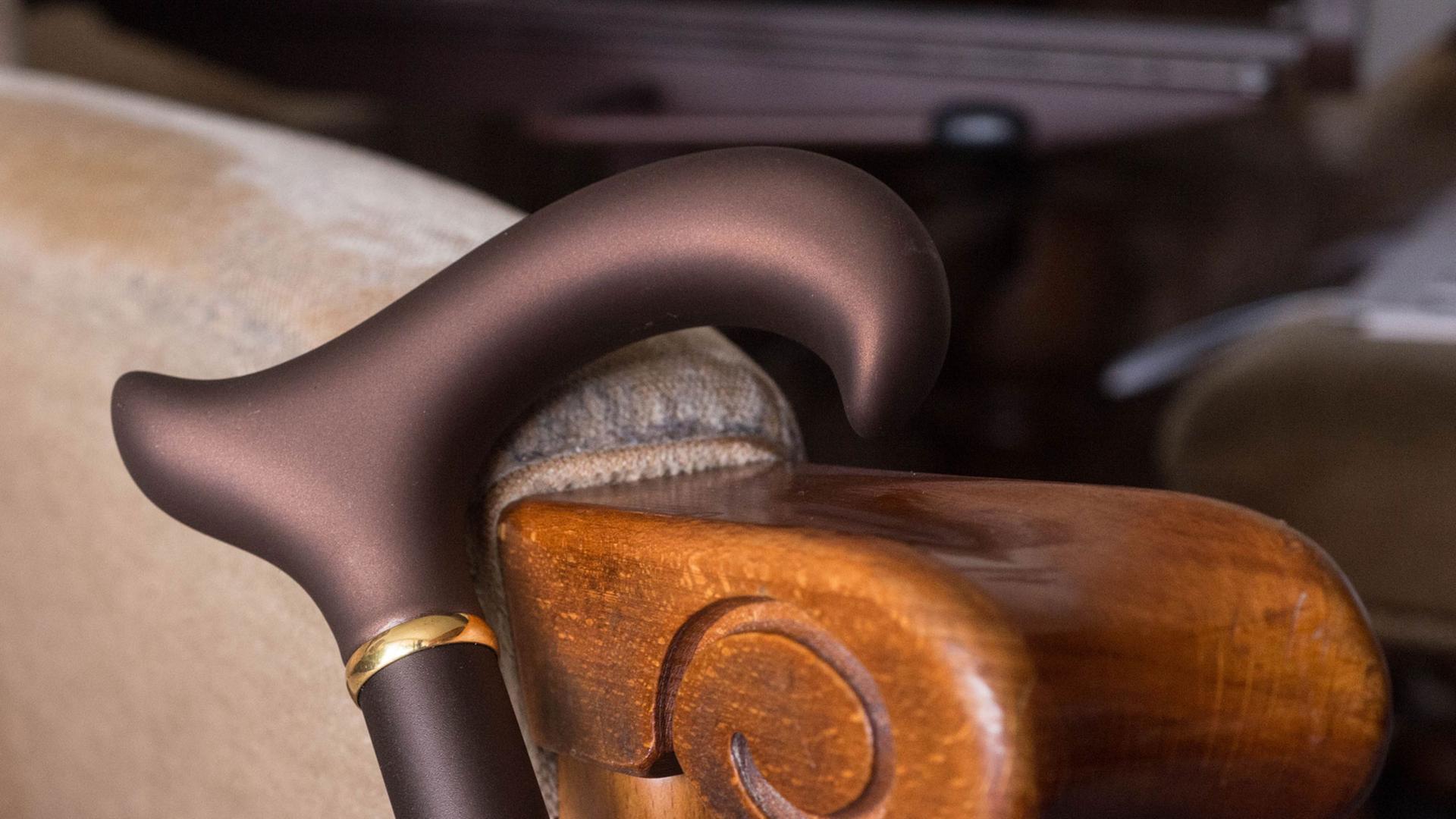 Ein brauner Krückstock lehnt an einem Sessel. Ein brauner Krückstock lehnt an einem Sessel.