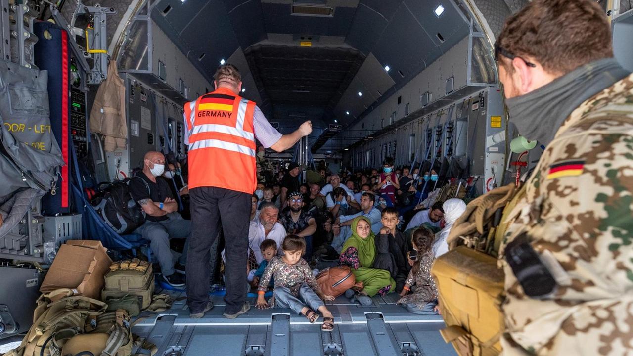 Eng gedrängte Flüchtende aus Afghanistan werden in einem Airbus der Bundeswehr von einem Koordinator mit Informationen versorgt. Eng gedrängte Flüchtende aus Afghanistan werden in einem Airbus der Bundeswehr von einem Koordinator mit Informationen versorgt.