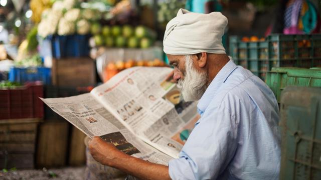 Ein Mann auf einem Markt in Munnar (Indien) liest eine Zeitung.