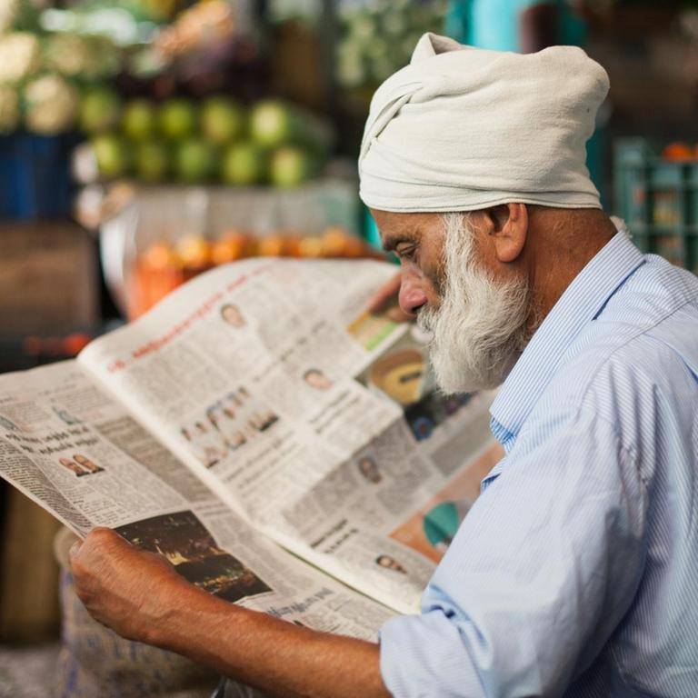 Ein Mann auf einem Markt in Munnar (Indien) liest eine Zeitung.
