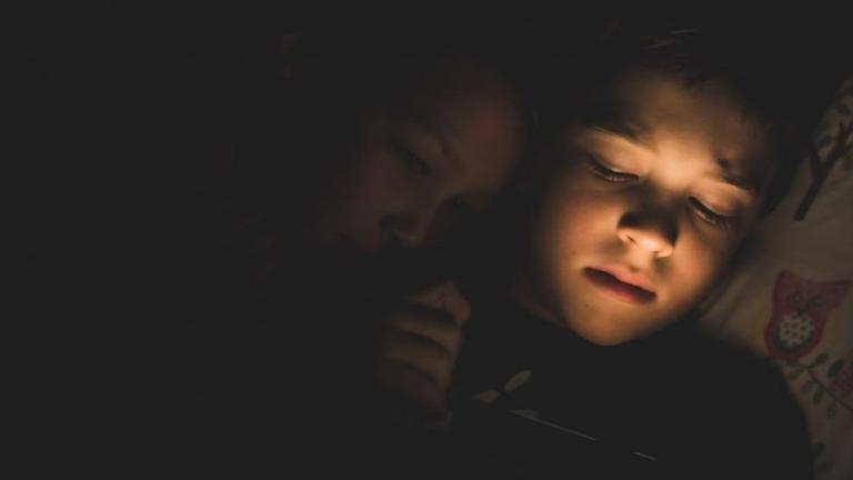 Zwei Kinder liegen im Bett, das Licht ist schon erloschen und sie sehen müde aus. Zwei Kinder liegen im Bett, das Licht ist schon erloschen und sie sehen müde aus.