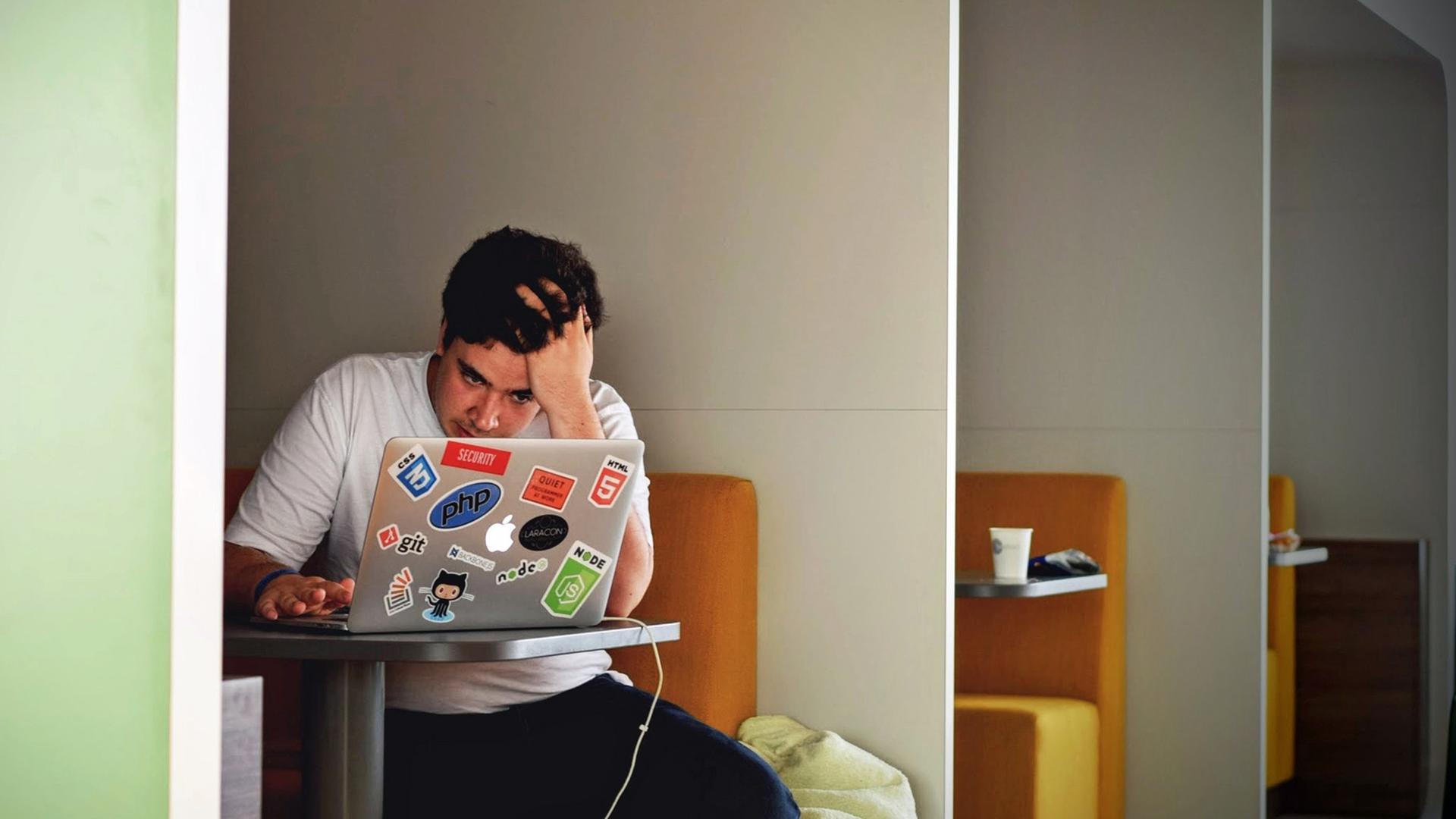 Ein junger Mann sitzt vor einem Laptop und rauft sich die Haare. Ein junger Mann sitzt vor einem Laptop und rauft sich die Haare.