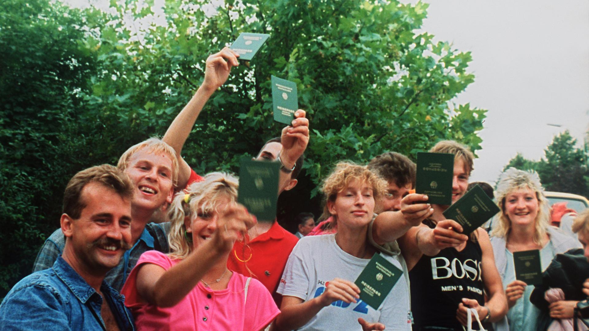Jubelnde DDR-Flüchtlinge mit ihren Reisepässen in Österreich. Etwa 600 DDR-Bürger nutzten ein paneuropäisches Picknick an der ungarisch-österreichischen Grenze, bei dem ein Grenztor symbolisch geöffnet wurde, zur Flucht in den Westen. Jubelnde DDR-Flüchtlinge mit ihren Reisepässen in Österreich. Etwa 600 DDR-Bürger nutzten ein paneuropäisches Picknick an der ungarisch-österreichischen Grenze, bei dem ein Grenztor symbolisch geöffnet wurde, zur Flucht in den Westen.