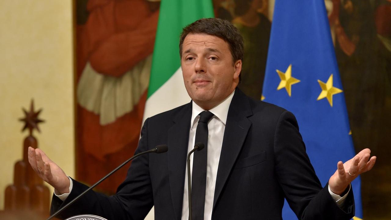 Sie sehen den italienischen Ministerpräsidenten Matteo Renzi. Er hat beide Hände erhoben.
