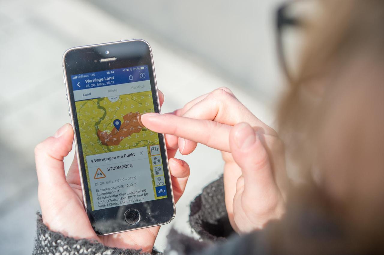 ILLUSTRATION - Eine Frau haelt am 21.03.2018 in Berlin ein Smartphone in der Hand, das eine Unwetter-Warnungs-App zeigt (gestellte Szene). Foto: Robert Guenther ILLUSTRATION - Eine Frau haelt am 21.03.2018 in Berlin ein Smartphone in der Hand, das eine Unwetter-Warnungs-App zeigt (gestellte Szene). Foto: Robert Guenther