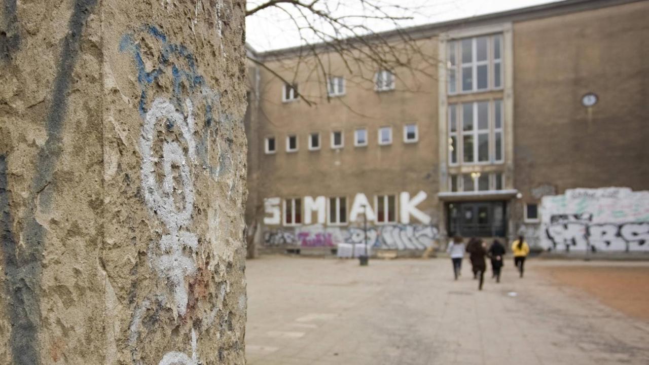 Grauer, bröckelnder Putz an einer Berliner Schule. 