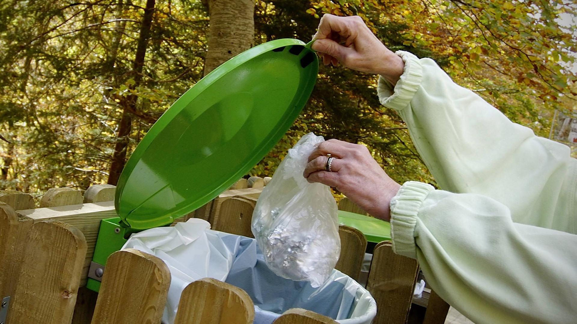 Plastikmüll wird in eine grüne Tonne geworfen. Plastikmüll wird in eine grüne Tonne geworfen.