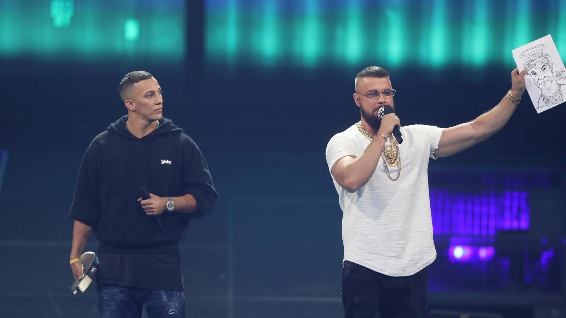 12.04.2018, Berlin: Kollegah (r) und Farid Bang erhalten den Echo für Album des Jahres bei der 27. Verleihung des Deutschen Musikpreises Echo. Die Rapper halten eine Karrikatur von Sänger Campino mit Heiligenschein hoch, welches sie versteigern wollen. Foto: Jörg Carstensen/dpa | Verwendung weltweit 12.04.2018, Berlin: Kollegah (r) und Farid Bang erhalten den Echo für Album des Jahres bei der 27. Verleihung des Deutschen Musikpreises Echo. Die Rapper halten eine Karrikatur von Sänger Campino mit Heiligenschein hoch, welches sie versteigern wollen. Foto: Jörg Carstensen/dpa | Verwendung weltweit