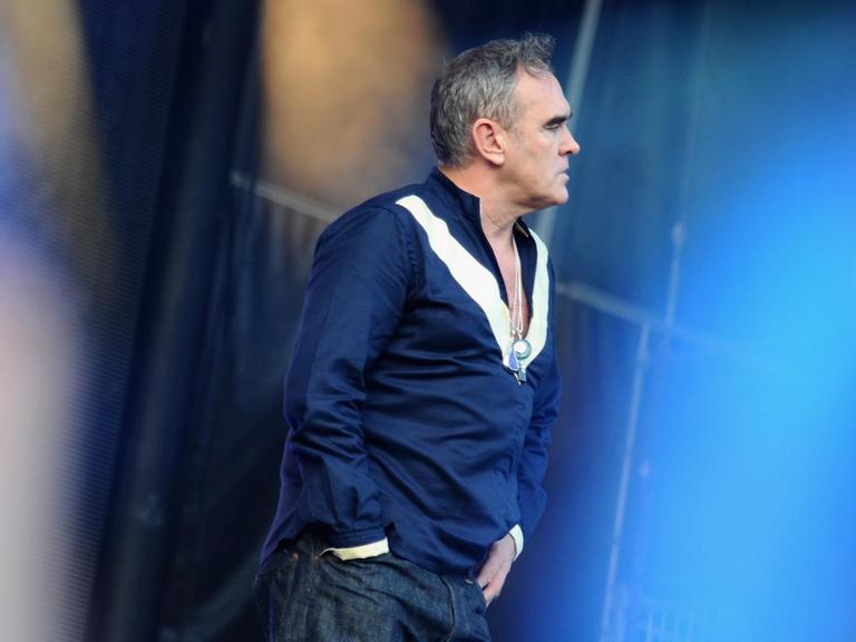Morrissey steht bei einem Live-Auftritt auf der Bühne und blickt nach rechts.