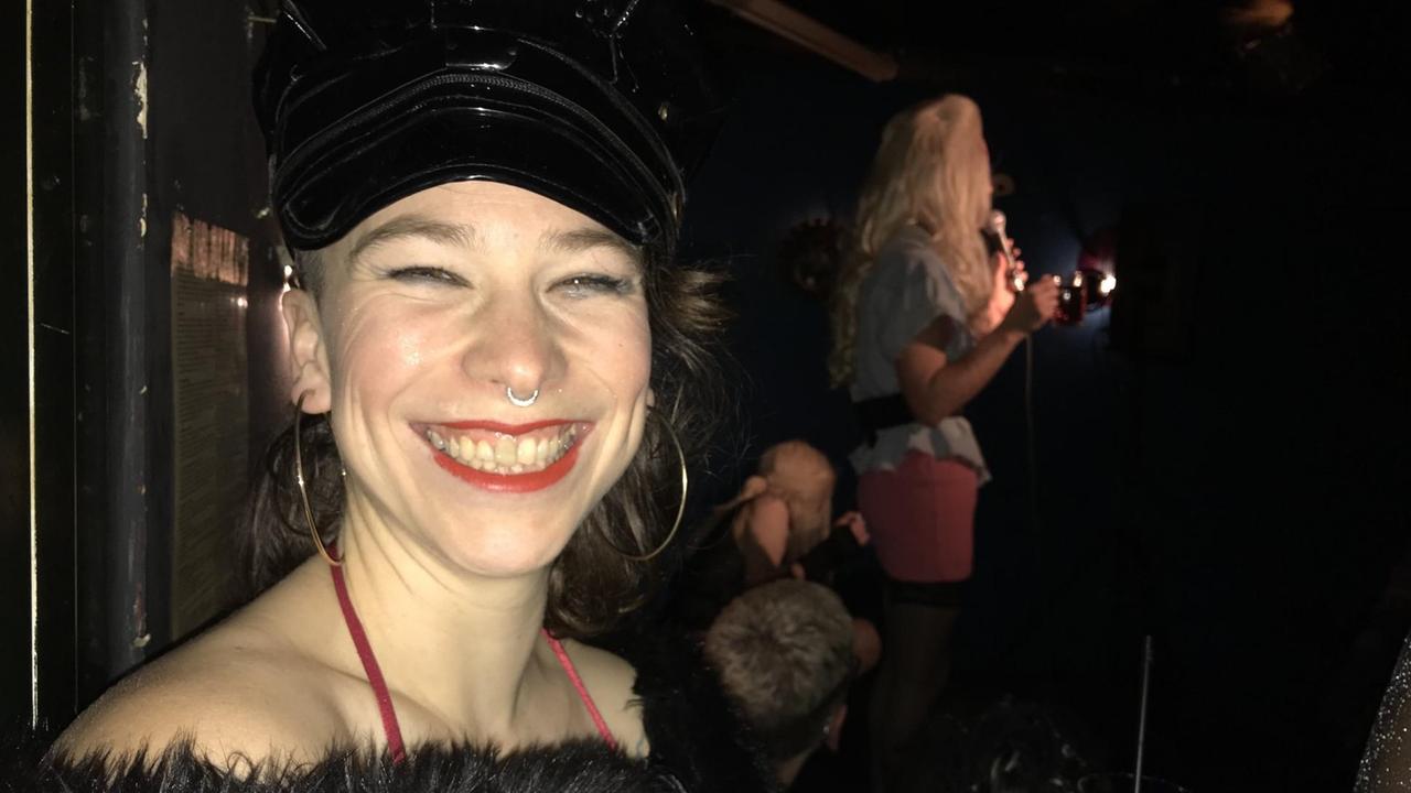 Pina lacht in einem Nachtclub frontal in die Kamera. Pina lacht in einem Nachtclub frontal in die Kamera.
