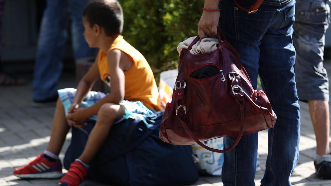 Ein Junge sitzt auf einer Tasche am Eingang zur Erstaufnahmeeinrichtung am 7. Juli 2015 in Dortmund Ein Junge sitzt auf einer Tasche am Eingang zur Erstaufnahmeeinrichtung am 7. Juli 2015 in Dortmund
