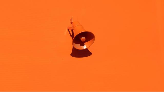 Ein orange angemalter Lautsprecher an einer orangenen Wand.