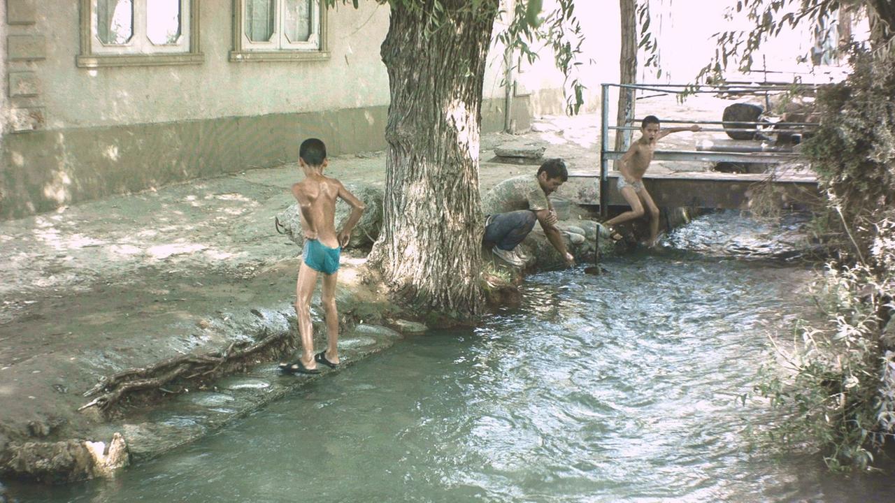 Kinder spielen in den Aryk-Kanälen - den traditionallen Wasserleitungen in Kirgistan, die in allen Städten sind. Kinder spielen in den Aryk-Kanälen - den traditionallen Wasserleitungen in Kirgistan, die in allen Städten sind.