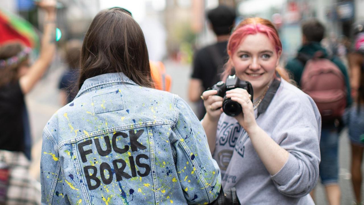 Zwei junge Frauen in England bei einer Anti-Boris-Johnson-Veranstaltung. Eine der Frauen trägt den Schriftzug "Fuck Boris" auf der Rückseite ihrer Jeansjacke.
