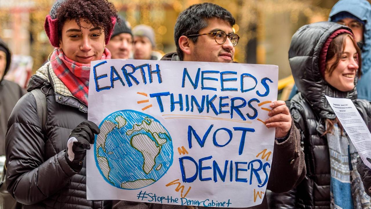 New Yorker demonstrieren gegen Trumps Kabinett, zu dem auch Personen gehören, die bestreiten, dass es einen Klimawandel gibt. Eine Frau hält ein Schild in der Hand, auf dem steht: "Earth needs thinkers not deniers". Die Erde braucht Denker, keine Leugner. New Yorker demonstrieren gegen Trumps Kabinett, zu dem auch Personen gehören, die bestreiten, dass es einen Klimawandel gibt. Eine Frau hält ein Schild in der Hand, auf dem steht: "Earth needs thinkers not deniers". Die Erde braucht Denker, keine Leugner.