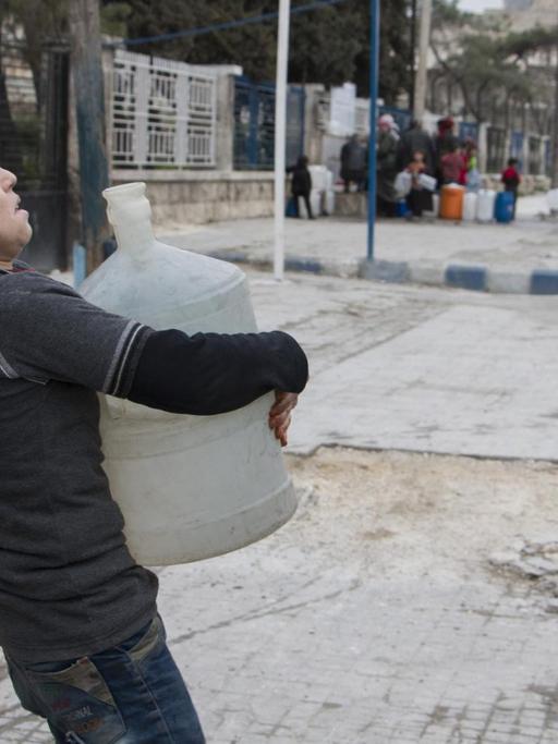 Ein Junge in Aleppo trägt einen Container mit Wasser.