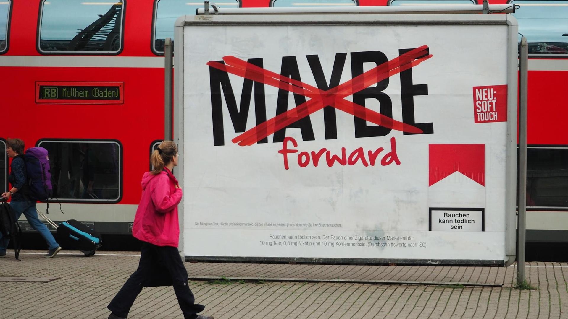 Eine Frau geht am Haupt-Bahn-Hof in Freiburg an einem Plakat mit Werbung für Zigaretten vorbei. Eine Frau geht am Haupt-Bahn-Hof in Freiburg an einem Plakat mit Werbung für Zigaretten vorbei.