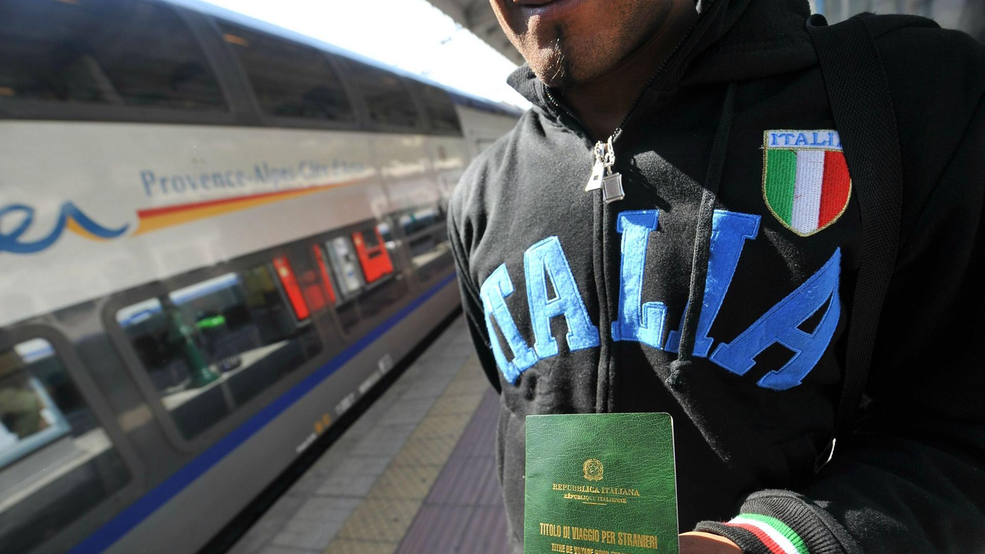 Ein illegaler Flüchtling zeigt am Bahnhof in der italienischen Grenzstadt Ventimiglia seine befristete Aufenthaltserlaubnis. Ein illegaler Flüchtling zeigt am Bahnhof in der italienischen Grenzstadt Ventimiglia seine befristete Aufenthaltserlaubnis.