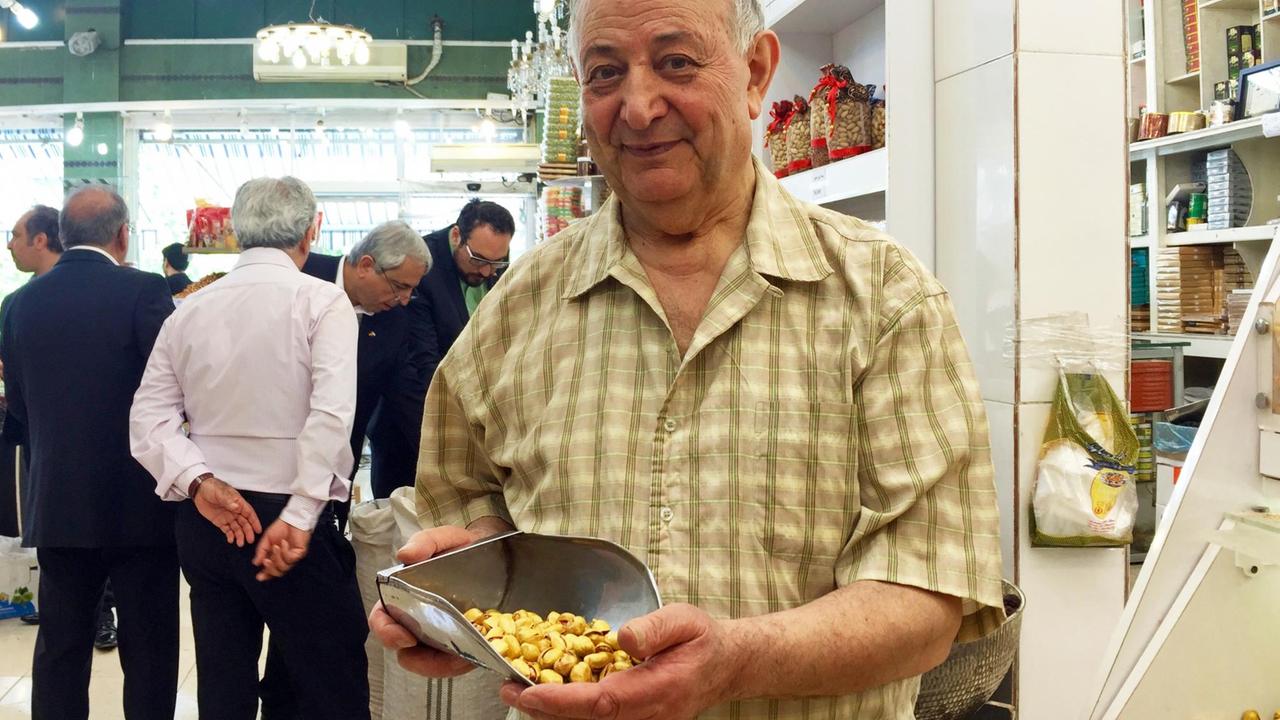 Dschalil Tavazo in seinem Geschäft mit einer Kelle voller Pistazien.